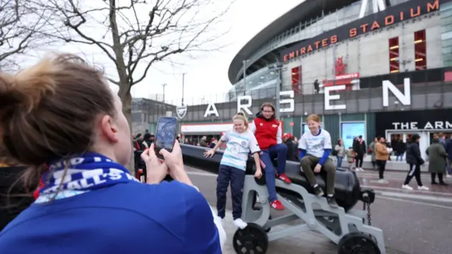 Fans posing outside Emirates Stadium