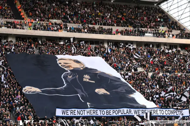 Newcastle fans unfurl a flag with the face of manager Eddie Howe.