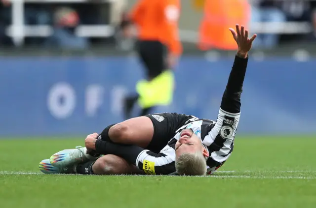 Newcastle midfielder Bruno Guimaraes goes down injured.