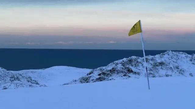 A snowy golf course overlooking the sea