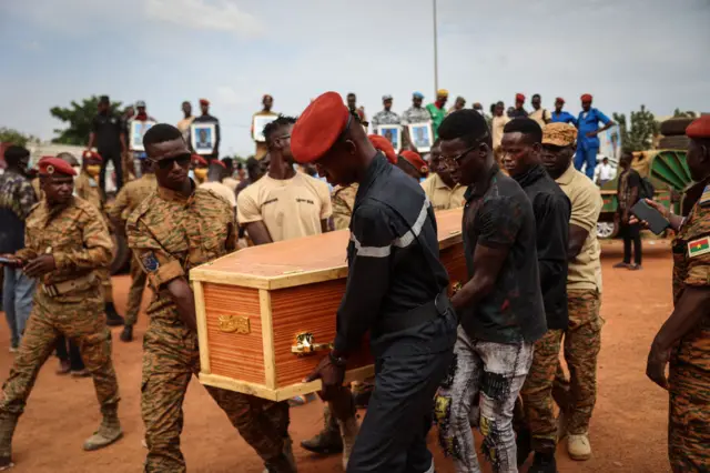 Burkina Faso's servicemen carry a coffin during the burial of the soldiers killed in Gaskinde, in Ouagadougou on October 8, 2022. - The ambush in Gaskinde, claimed by Al-Qaeda, officially killed 37 people, including 27 soldiers on September 26, 2022