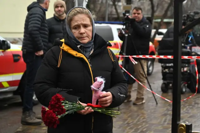 A woman brings flowers to pay tribute to the dead