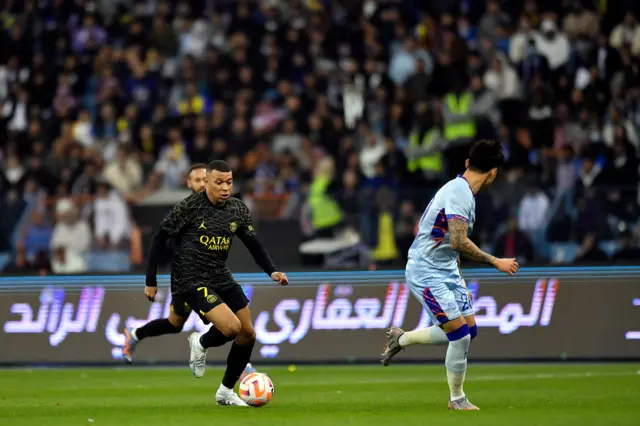 Kylian Mbappe running with pace at Allstars right-back Sultan Al Ghanam and taking him on