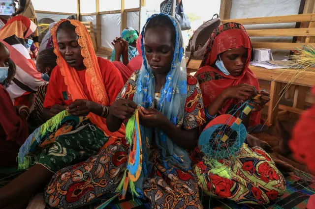 A group of women make fans in a workshop given by members of the NGO, Plan International, during a visit by Filippo Grandi, the United Nations High Commissioner for Refugees (UNHCR), in Maroua on April 28, 2022