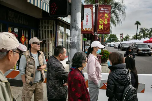 Community members watch as officials secure and investigate the scene