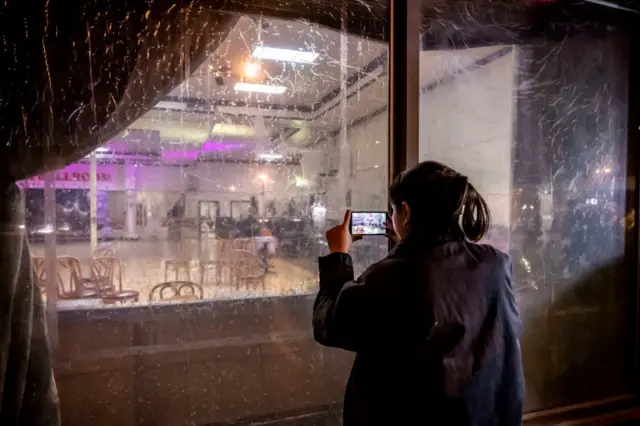 A woman takes cell phone photos of the dance studio