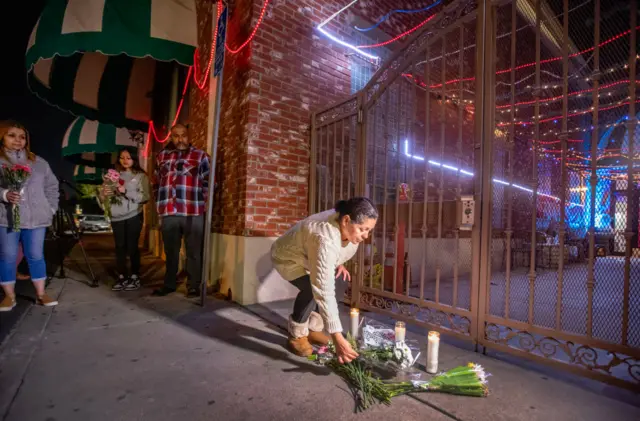 A woman lays flowers at the entrance to the dance studio