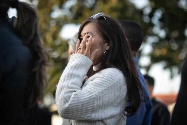 A woman wipes away tears as she prays at the vigil