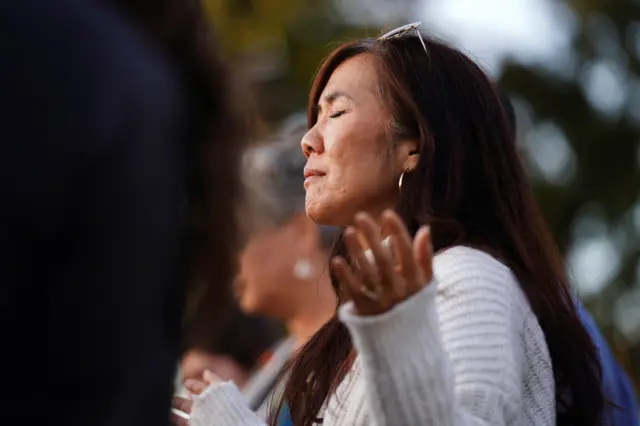 A woman holds her arms up in prayer