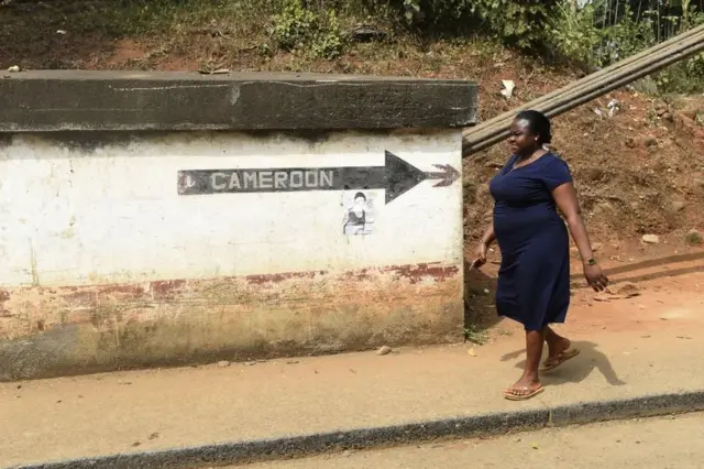 A woman walks from Cameroon into Nigeria.