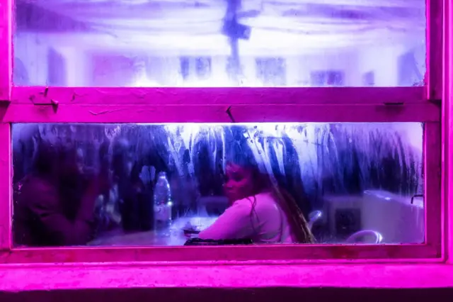 A woman looks out the window of a bar along Virage beach in Dakar on 21 January.