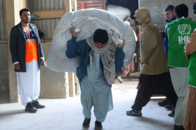 An Afghan worker unloads sacks of food from a Turkish aid train to Afghanistan at Turghundi border port, in Kushk district of Herat province on In this picture taken on 23 January 2023