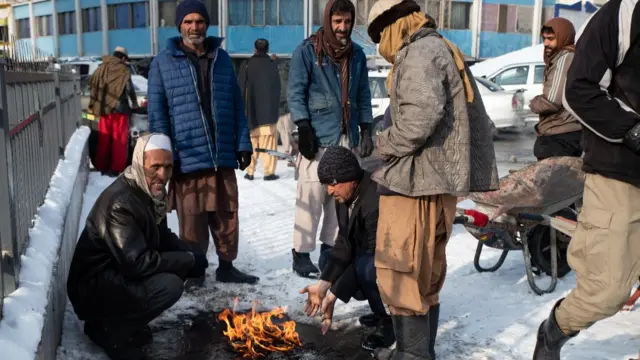 Men in Kabul stand around a fire on the street