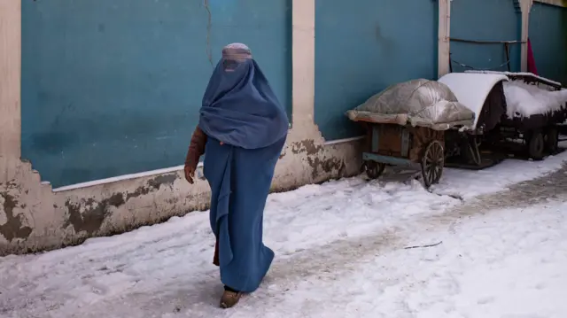 A woman walks on a street in Kabul