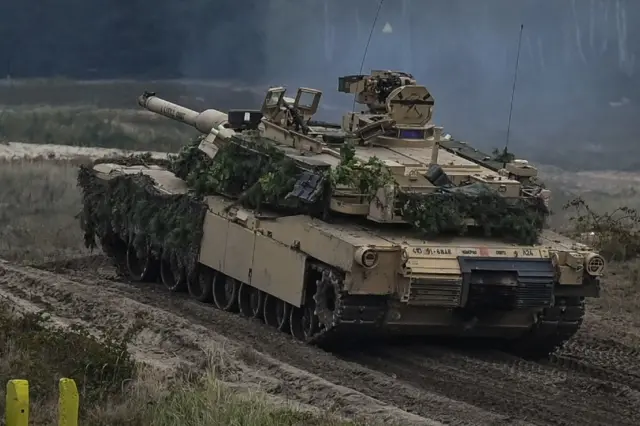 An American-made Abrams tank travels over muddy terrain