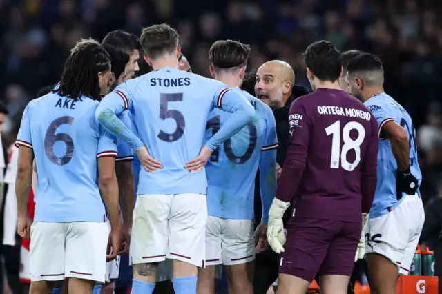 Manchester City players receive instructions from Pep Guardiola