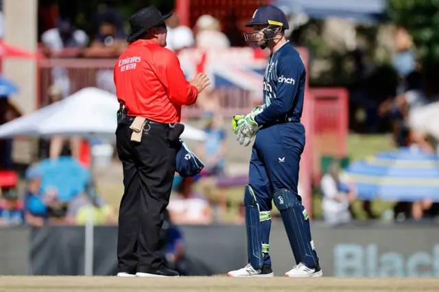 South African umpire Marais Erasmus (L) speaks with England's Jos Buttler (R) during the second one day international (ODI) cricket match between South Africa and England at Mangaung Oval