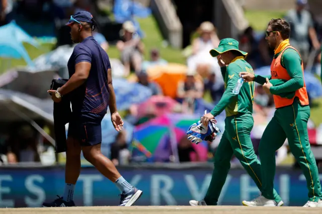 Quinton de Kock walks off the field after taking a blow to the right hand