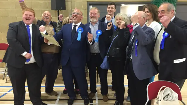 Nadhm Zahawi wearing a blue rosette and cheering with colleagues