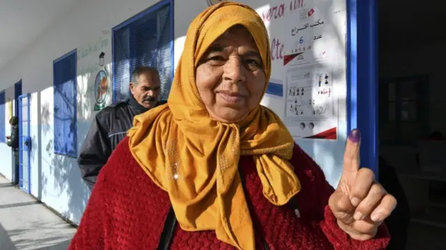 A Tunisian voter displays their ink-stained finger after casting their ballot at a polling station for the second-round of parliamentary elections in Ettadhamen, a suburb west of the capital Tunis - 29 January 2023