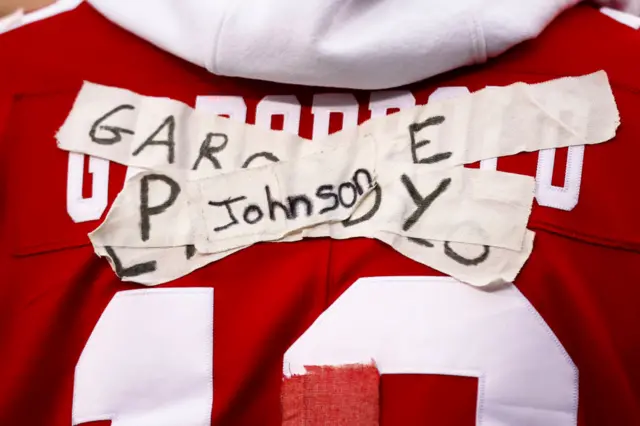 San Francisco 49ers fan with different quarterback names taped on the back of their jersey because of injuries