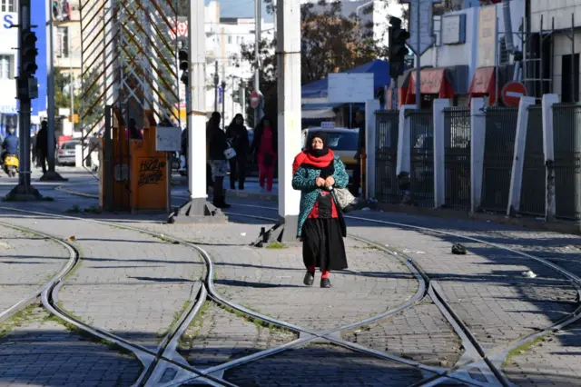 A Tunisian woman is pictured next to a tram station in the capital Tunis, on January 2, 2023