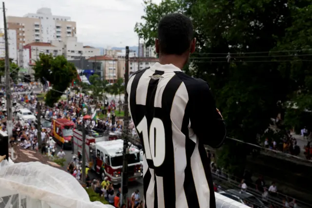 A mourner wearing a Santos shirt watching the procession