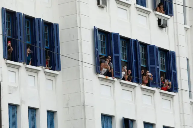 Mourners looking through office windows to watch Pele's funeral procession