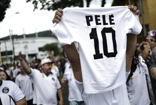 A fan holding up a Pele Santos shirt