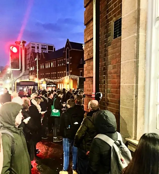 A crowd of people wait in the dark outside a closed Brentwood station early on Tuesday morning