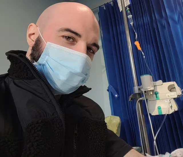 Tyler Davis poses for a photo in a medical environment wearing a face mask