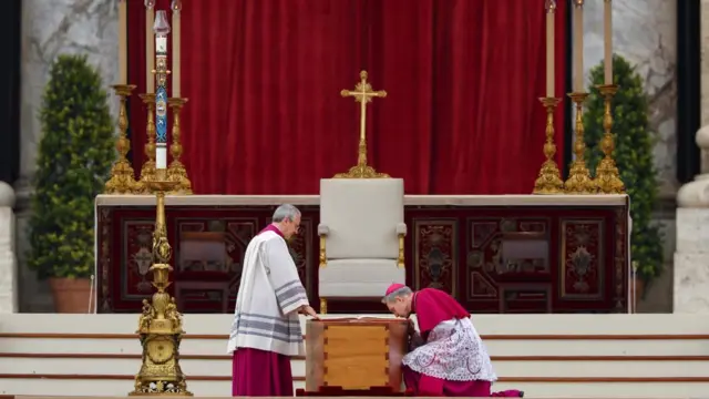 Archbishop Georg Gaenswein kisses the Bible on top of former Pope Benedict's coffin during his funeral, in St. Peter's Square at the Vatican