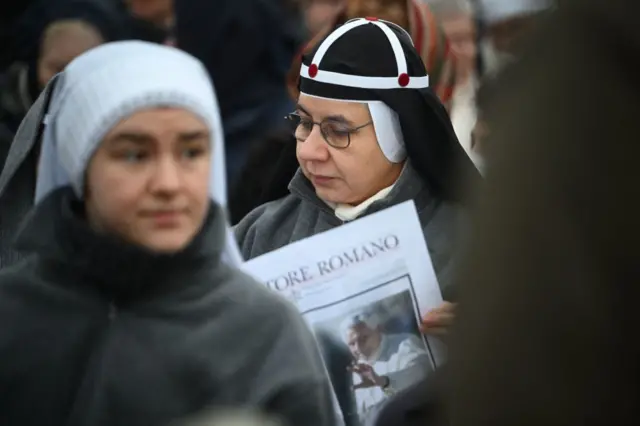 A nun reads the Osservatore Romano Catholic newspaper as she waits prior to the funeral mass