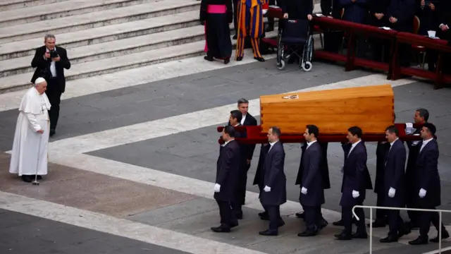 Pallbearers move the coffin