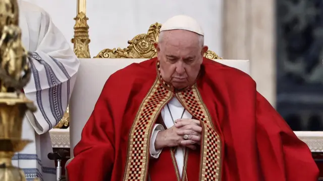 Pope Francis sitting with his hands clasped and eyes closed