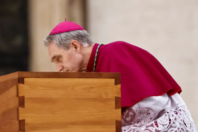 Archbishop Georg Gaenswein kisses the coffin of former Pope Benedict