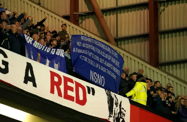 Everton fans hold up a banner against the board