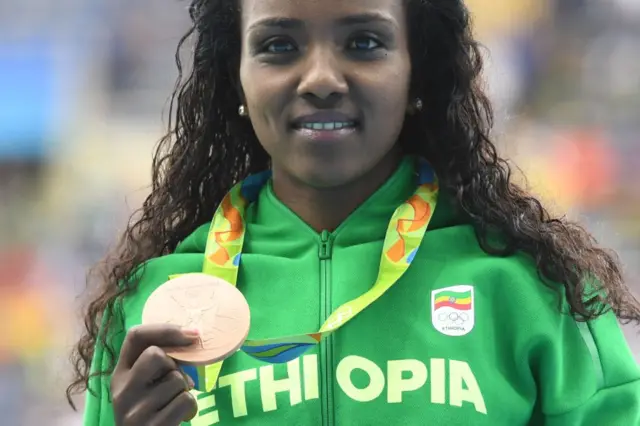 Ethiopia's Tirunesh Dibaba holds up her medal on the podium after the Women's 10,000m athletics event at the Rio 2016 Olympic Games at the Olympic Stadium in Rio de Janeiro on August 12, 2016