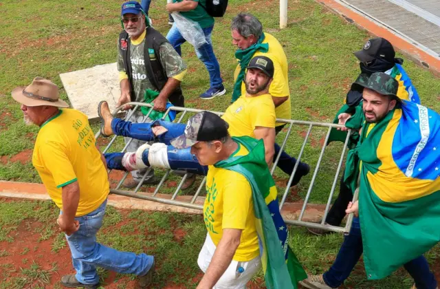 A wounded protester being carried on a piece of fencing