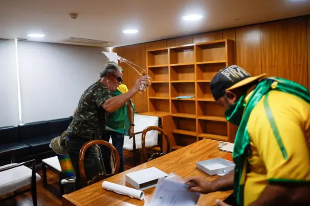 Protesters breaking stuff inside an office