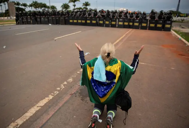 A supporter of Brazil's far-right former President Jair Bolsonaro prays in front of police officers during protests