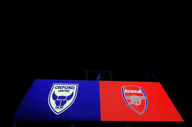 The scoreboard at the Kassam Stadium shows the badges of Oxford United and Arsenal