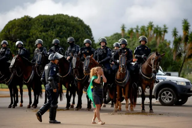 A demonstrator reacts next to members of security forces near Army headquarters in Brasilia