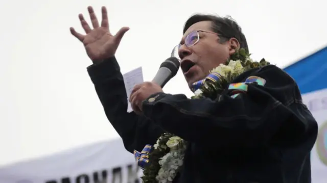 Bolivia's president Luis Arce addressing a crowd. He is speaking into a microphone.