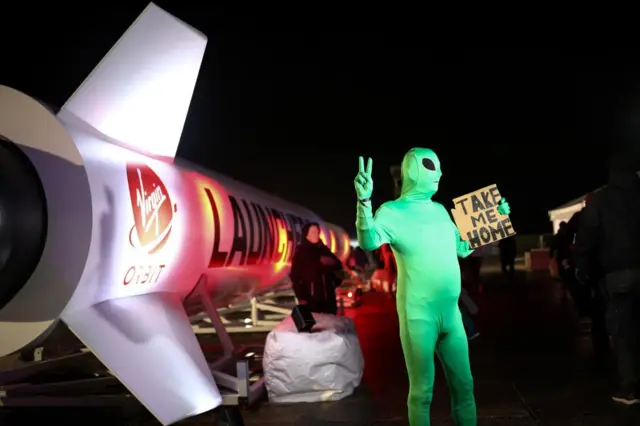 A person wearing an alien costume poses for a photographer during a spectator event for Virgin Orbit's LauncherOne first UK launch from Spaceport Cornwall at Cornwall Airport Newquay in Newquay, Britain, January 9, 2023.