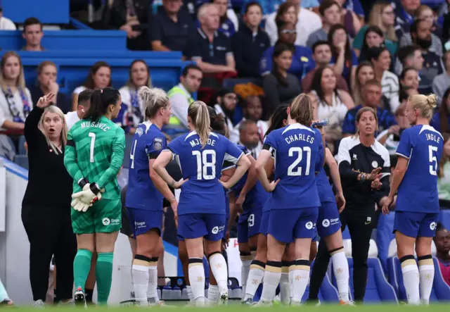 Hayes calls her players over for a tactical briefing on the touchline.