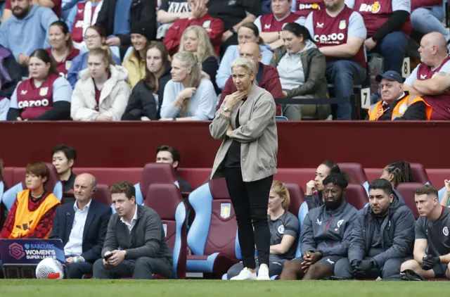 Carla Ward watches on while standing in front of the dugout.