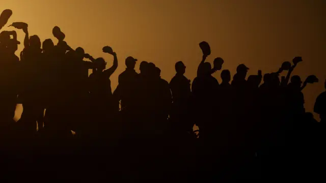 Supporters wave their hats