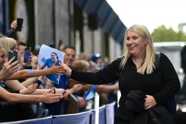 Emma Hayes high fives young fans as she walks into the stadium from the bus.