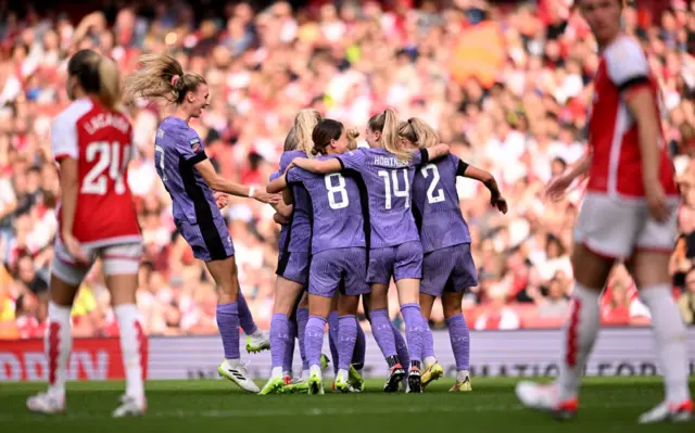 Liverpool players huddle to celebrate as Arsenal players trudge back to kick off.